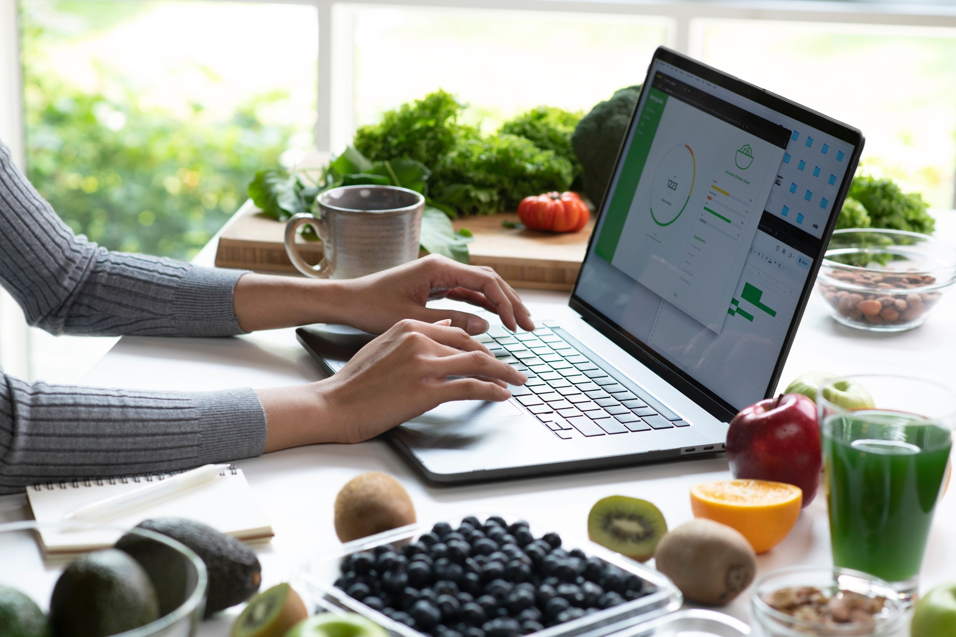 Woman Asian Professional Nutritionist busy working and checking data from a laptop with a variety of fruits, nuts, vegetables, and dietary supplements on the table